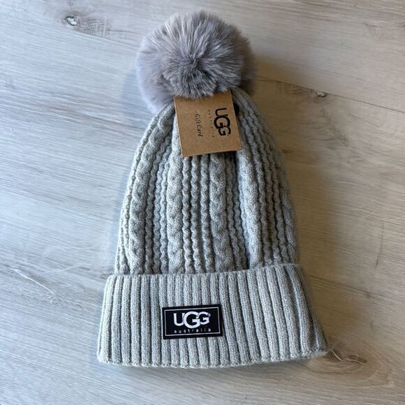 UGG KNIT CABLE HAT WITH FAUX FUR POM LIGHT GREY NWT - Picture 1 of 3